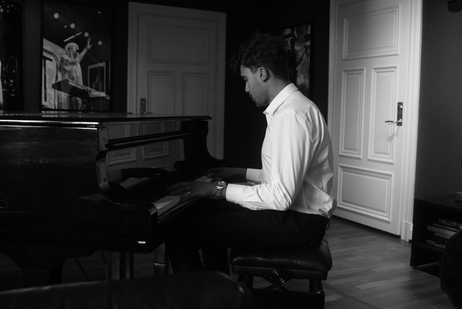 A young man in a white shirt at a grand piano, in black and white